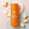 Orange bottle of Claress Crema Despigmentante Corporal on a light background with cream and soap bars.